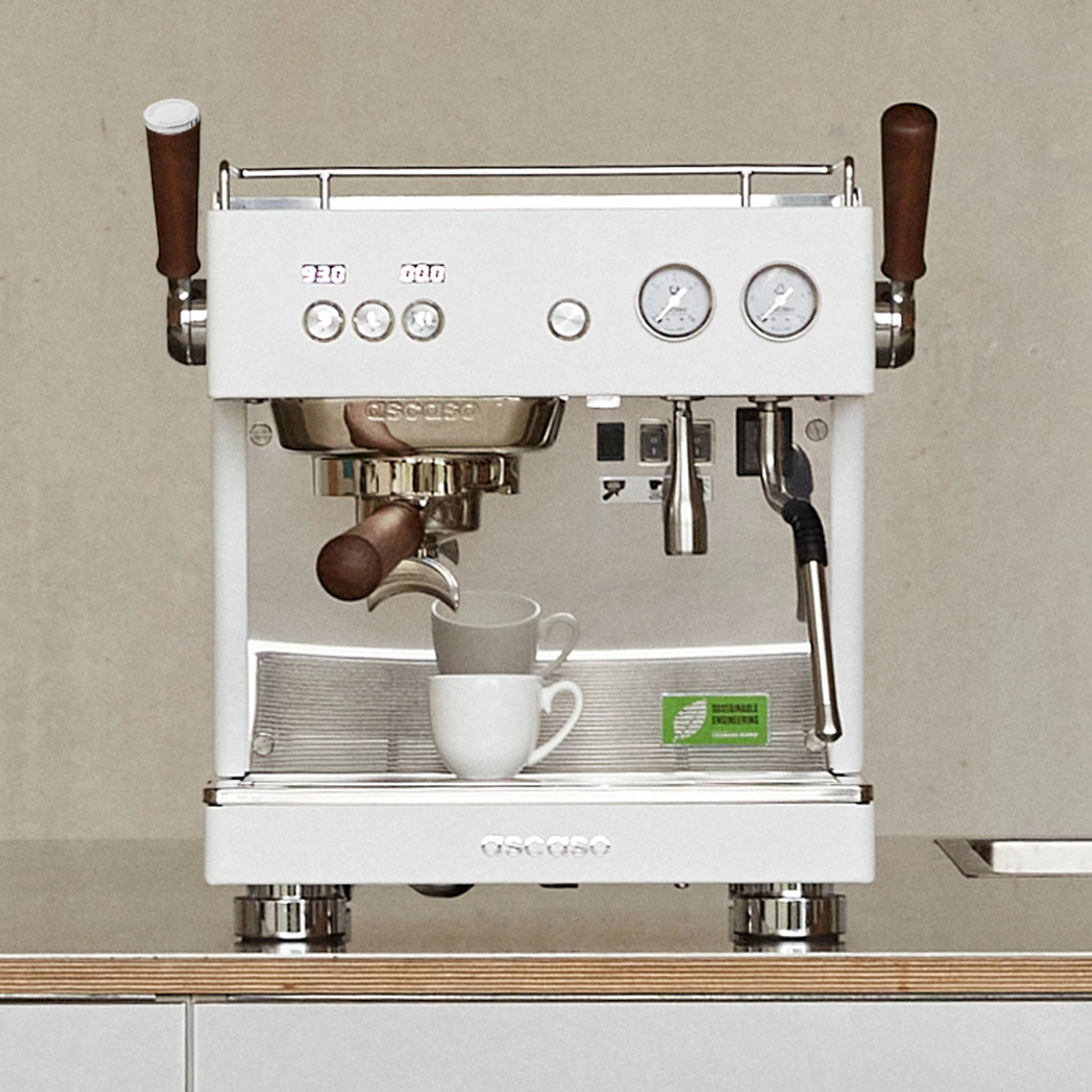 White „Ascaso“ Baby T FLOW on a counter next to a plant