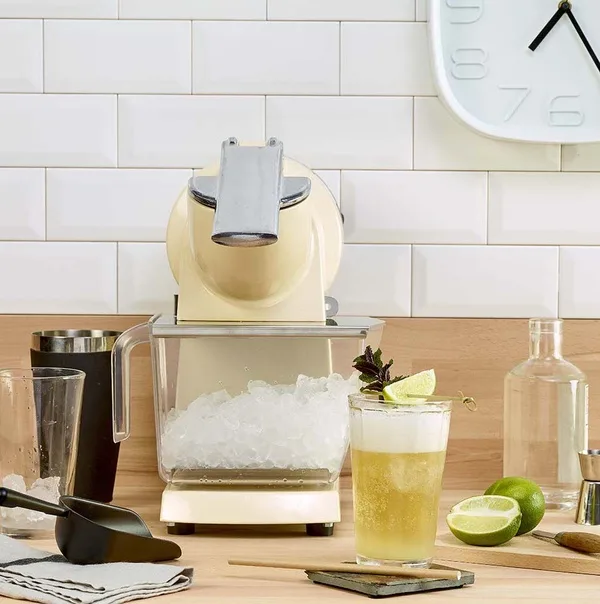 „Santos“ #09 ice crusher with a drawer full of crushed ice, next to a cocktail with lime