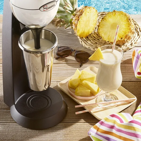„Santos“ #54 drink mixer with the stainless steel cup, next to a creamy drink and pineapple