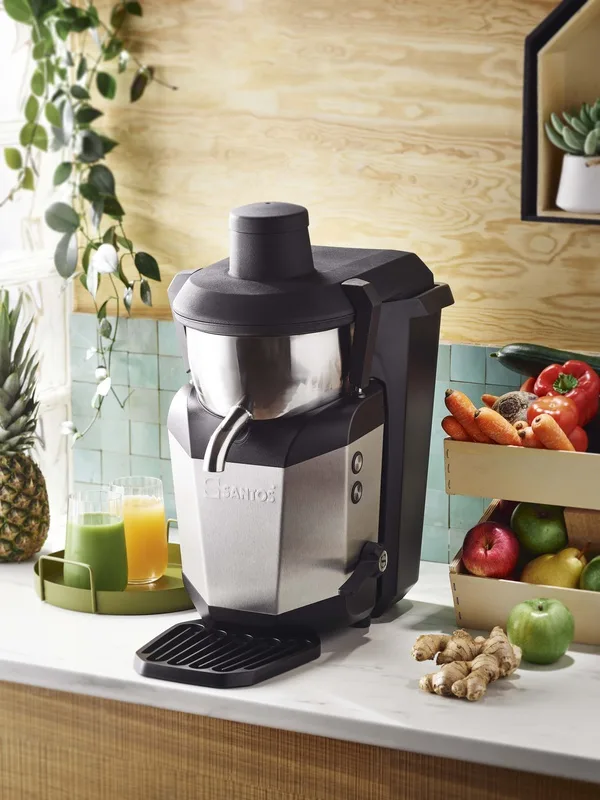 „Santos“ #50 centrifugal juicer on a counter with glasses of juice, fruit and vegetables