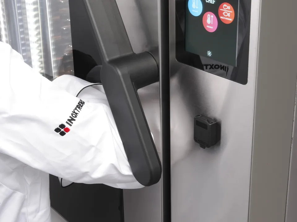 A chef opens the door of an „Inoxtrend“ Flexo oven with an elbow on the ergonomic handle